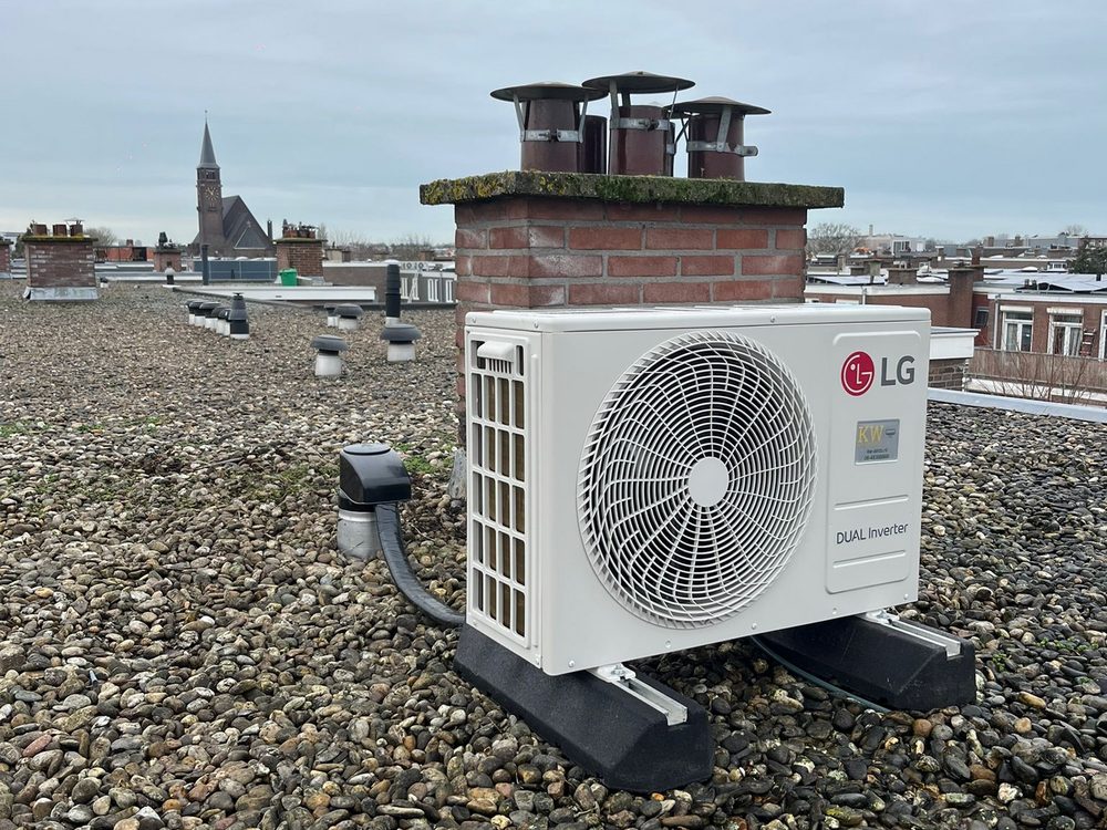 LG buitenunit op grinddak achter schoorsteen met Haags stadsgezicht