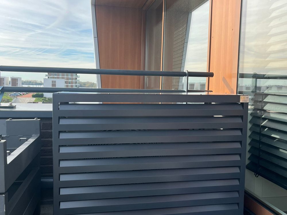 Airco buitenunit in antraciet omkasting op balkon van appartement